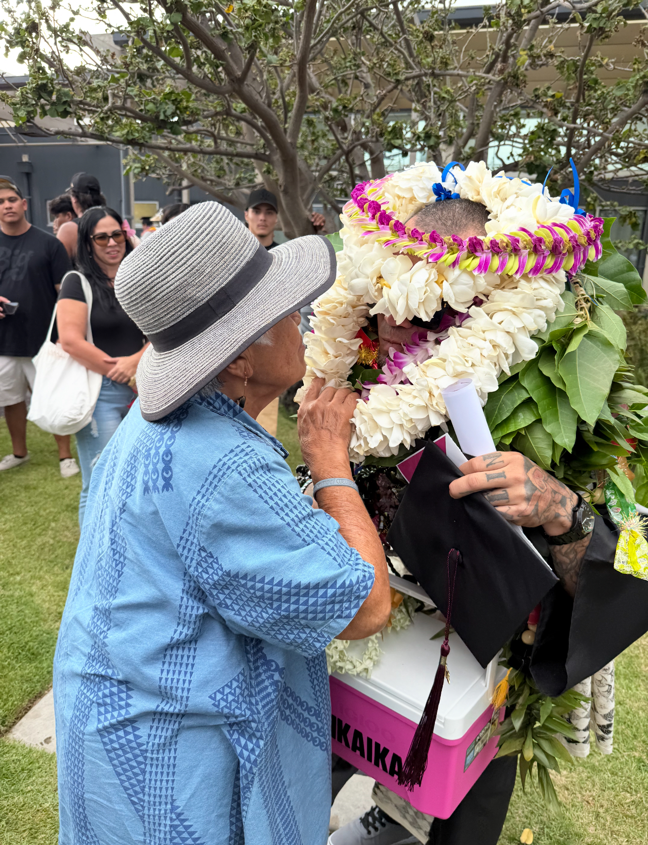 Camacho, covered in lei to the top of his head, is greeted by his grandmother after the ceremony.