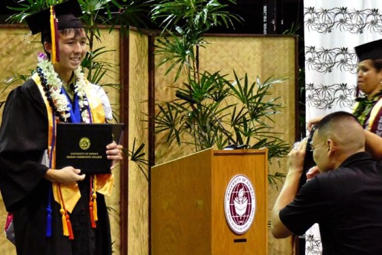 Craig Okahara-Olsen with his degree at commencement